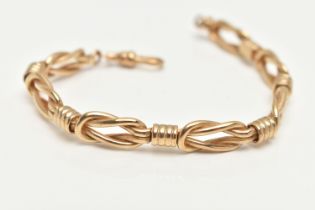 A YELLOW METAL FANCY LINK BRACELET, comprised of seven lovers knots, fitted with a spring clasp,