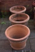 A PAIR OF CYLINDRICAL TAPERED TERRACOTTA PLANTERS, diameter 56cm x height 41cm along with another