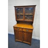 AN EARLY 20TH CENTURY OAK BOOKCASE, with double glazed doors, over a base with two drawers, and