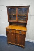 AN EARLY 20TH CENTURY OAK BOOKCASE, with double glazed doors, over a base with two drawers, and
