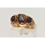 A LATE 19TH CENTURY 9CT GOLD THREE STONE RING, central oval cut garnet set with two oval cut red