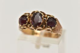 A LATE 19TH CENTURY 9CT GOLD THREE STONE RING, central oval cut garnet set with two oval cut red