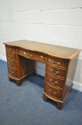 A BEVAN FUNNELL REPRODUCTION WALNUT SERPENTINE DESK, with a green leather writing surface, nine