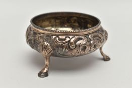 A VICTORIAN SILVER CIRCULAR OPEN SALT, repoussé decorated with flowers and scrolls, on three