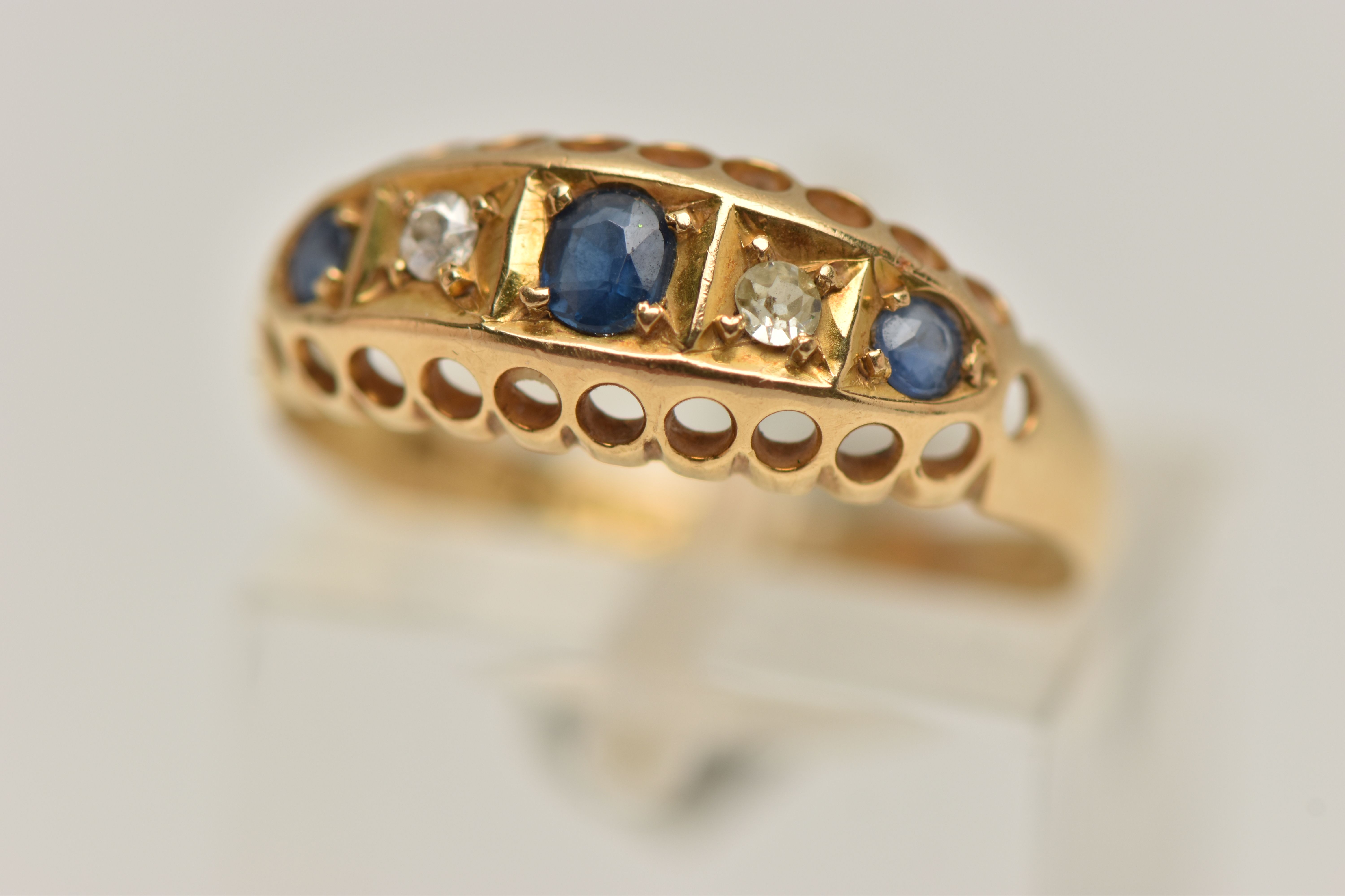 AN EARLY 20TH CENTURY 18CT GOLD BOAT RING, set with three circular cut blue sapphires interspaced
