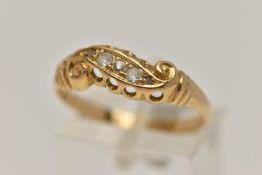 A YELLOW METAL DIAMOND RING, set with five graduated diamonds, within a scroll mount, leading onto a