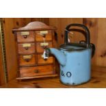 A SMALL SPICE CABINET AND A BLUE ENAMEL HOT WATER POT, comprising a seven drawer spice cabinet,