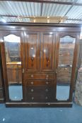 AN EDWARDIAN MAHOGANY COMPACTUM WARDROBE, with two mirrored doors, flanking two cupboard doors,