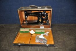 A VINTAGE CASED SINGER SEWING MACHINE in alligator skin style case with a quantity of accessories