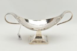 A GEORGE V PLANISHED SILVER ARTS AND CRAFTS TWIN HANDLED OVAL PEDESTAL BOWL, the elongated scroll