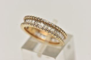 A YELLOW METAL DIAMOND BAND RING, set with a central row of baguette cut diamonds, between two