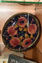A WILLIAM MOORCROFT SHALLOW FRUIT BOWL DECORATED WITH THE POMEGRANATE PATTERN ON A BLUE / BROWN