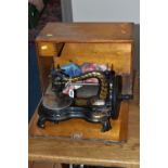 A CASED JONES HAND SEWING MACHINE, swan neck, in black with rubbed gilt decoration, some paint