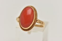 A YELLOW METAL CORAL RING, oval coral cabochon, collet set in yellow metal with rope detail