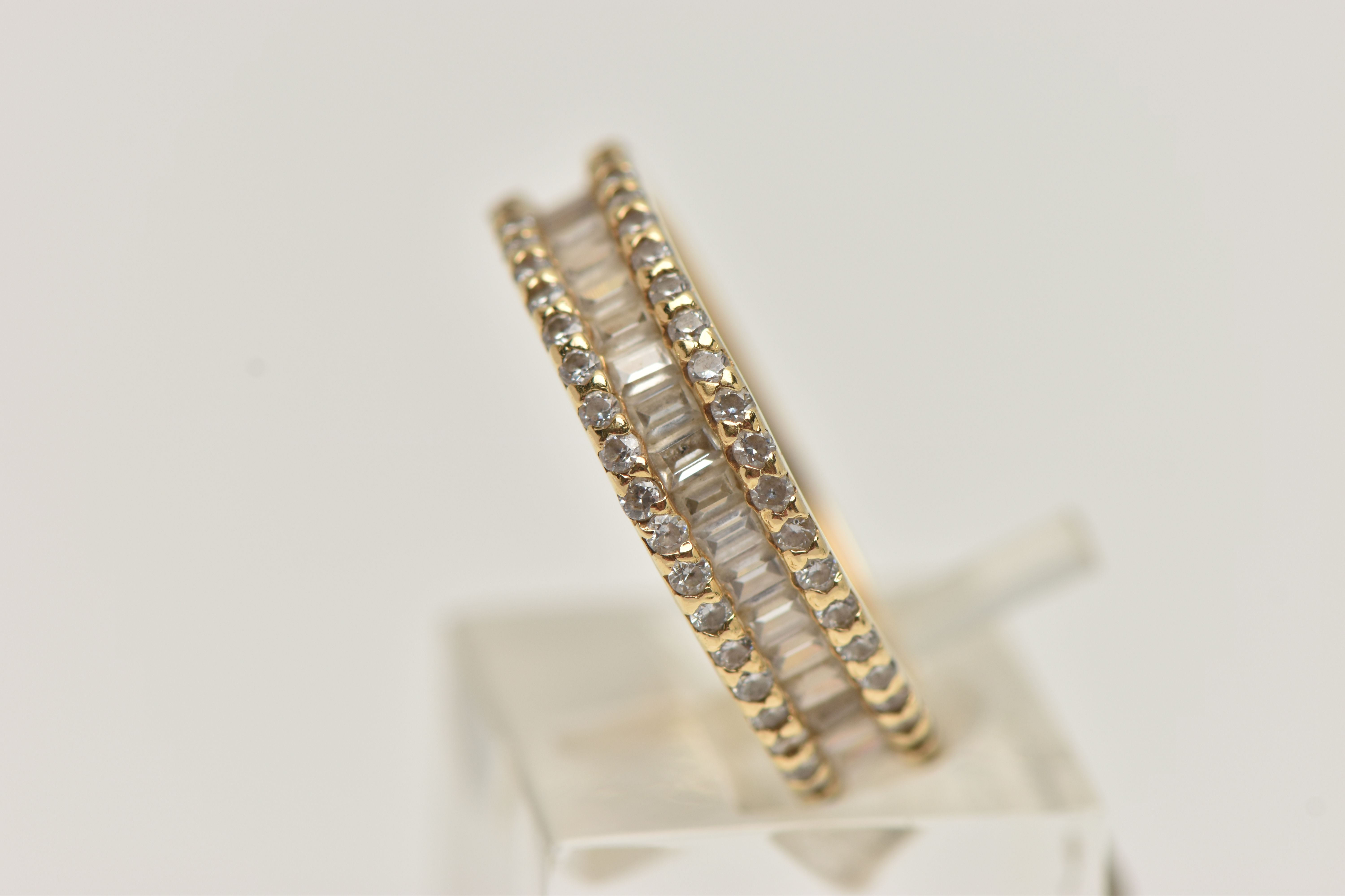 A YELLOW METAL DIAMOND BAND RING, set with a central row of baguette cut diamonds, between two - Image 2 of 4
