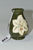 A MOORCROFT POTTERY BALUSTER VASE DECORATED WITH WHITE LILIES ON A GREEN GROUND, impressed marks and