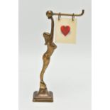 AN ART DECO BRASS FEMALE NUDE BRIDGE MARKER, the figure holding a bar with five double sided suits /