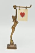 AN ART DECO BRASS FEMALE NUDE BRIDGE MARKER, the figure holding a bar with five double sided suits /