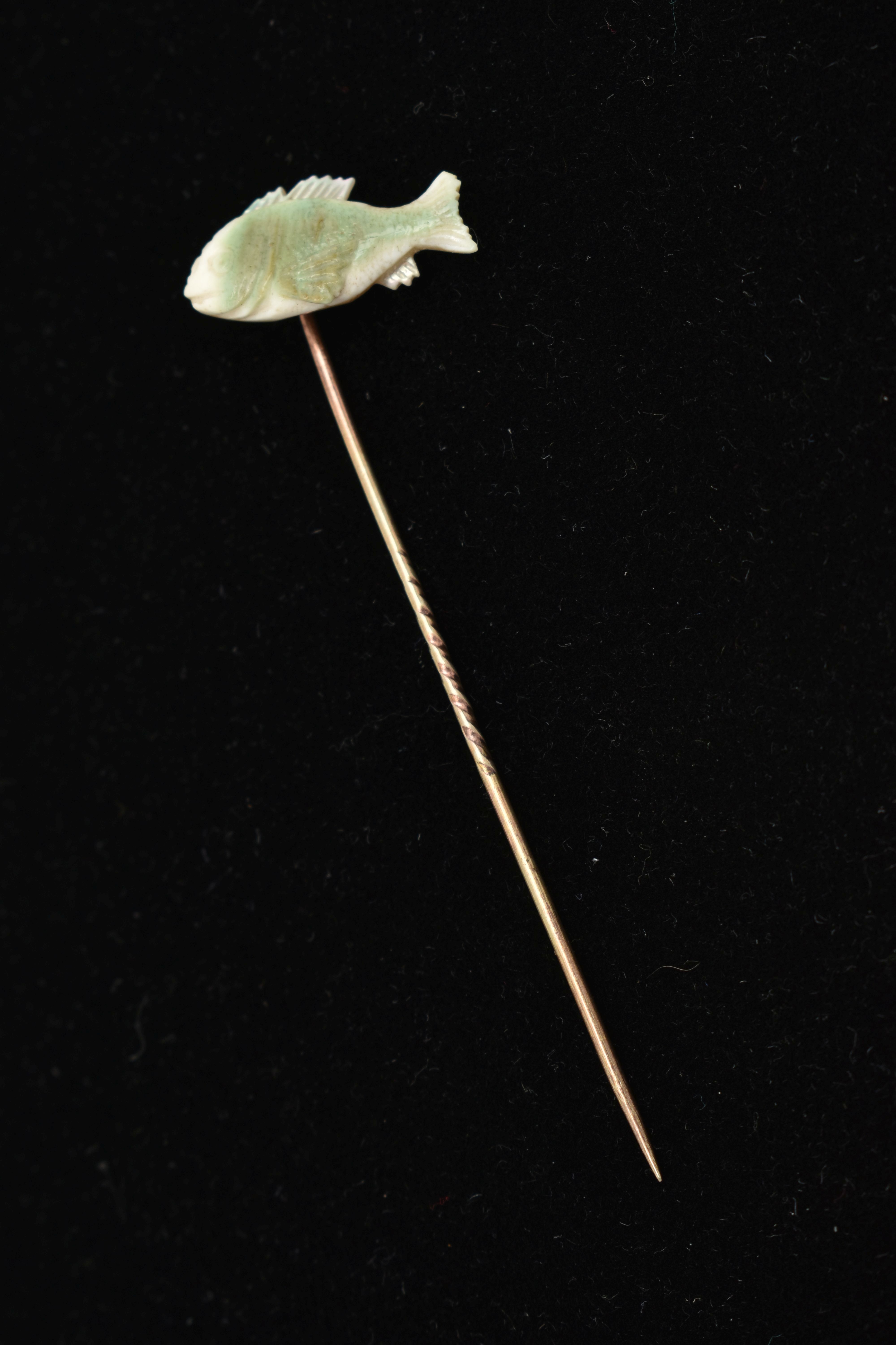 A YELLOW METAL MOTHER OF PEARL STICK PIN, set with a carved mother of pearl fish, to a yellow