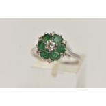 A WHITE METAL EMERALD AND DIAMOND CLUSTER RING, circular cluster, set with a central raised round