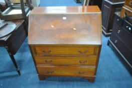 A 20TH CENTURY MAHOGANY BUREAU, the fall front door enclosing a fitted interior, above three