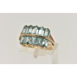 A 9CT GOLD TOPAZ DRESS RING, designed with two rows of rectangular cut light blue topaz, trifurcated