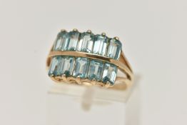 A 9CT GOLD TOPAZ DRESS RING, designed with two rows of rectangular cut light blue topaz, trifurcated