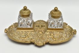 A LATE VICTORIAN BRASS INKSTAND FITTED WITH TWO SQUARE MOULDED GLASS INKWELLS, the stand cast with