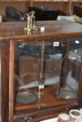 A SET OF BALANCE SCALES, housed in a glazed oak case, approximate height of case 52cm, together with