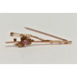 A YELLOW METAL RUBY SET BAR BROOCH, polished bar with flower detail set with a circular cut ruby,