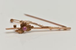 A YELLOW METAL RUBY SET BAR BROOCH, polished bar with flower detail set with a circular cut ruby,