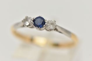 A YELLOW METAL THREE STONE RING, set with a central circular cut blue sapphire, flanked with