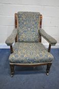 A GEORGE V MAHOGANY DEEP ARMCHAIR, with beige and blue floral upholstery, open armrests, on turned
