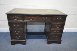 A REPRODUCTION MAHOGANY PEDESTAL DESK, with green leather writing surface, and an arrangement of