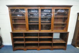 AN EDWARDIAN WALNUT BOOKCASE, the top section with four glazed doors, enclosing a variety of