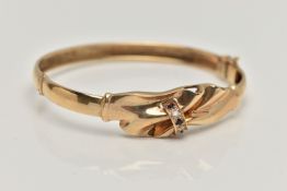 A 9CT GOLD HINGED BANGLE, gathered swag detail, set with three circular cut blue sapphires and two