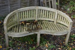 A WEATHERED TEAK CURVED BANANA BENCH, length 151cm (condition report: left art rickety)
