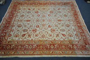 A 20TH CENTURY RED AND CREAM FOLIATE PATTERNED RUG, with a repeating central field and a multi strap
