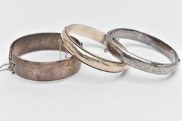 THREE SILVER BANGLES, to include a wide hinged bangle, foliage pattern, push piece clasp, with