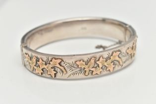 A MID 20TH CENTURY SILVER HINGED BANGLE, yellow metal ivy leaf detail to the one side, push button