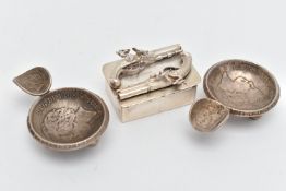 A WHITE METAL SNUFF BOX AND TWO ASHTRAYS, rectangular box featuring two Flintlocks to the hinged