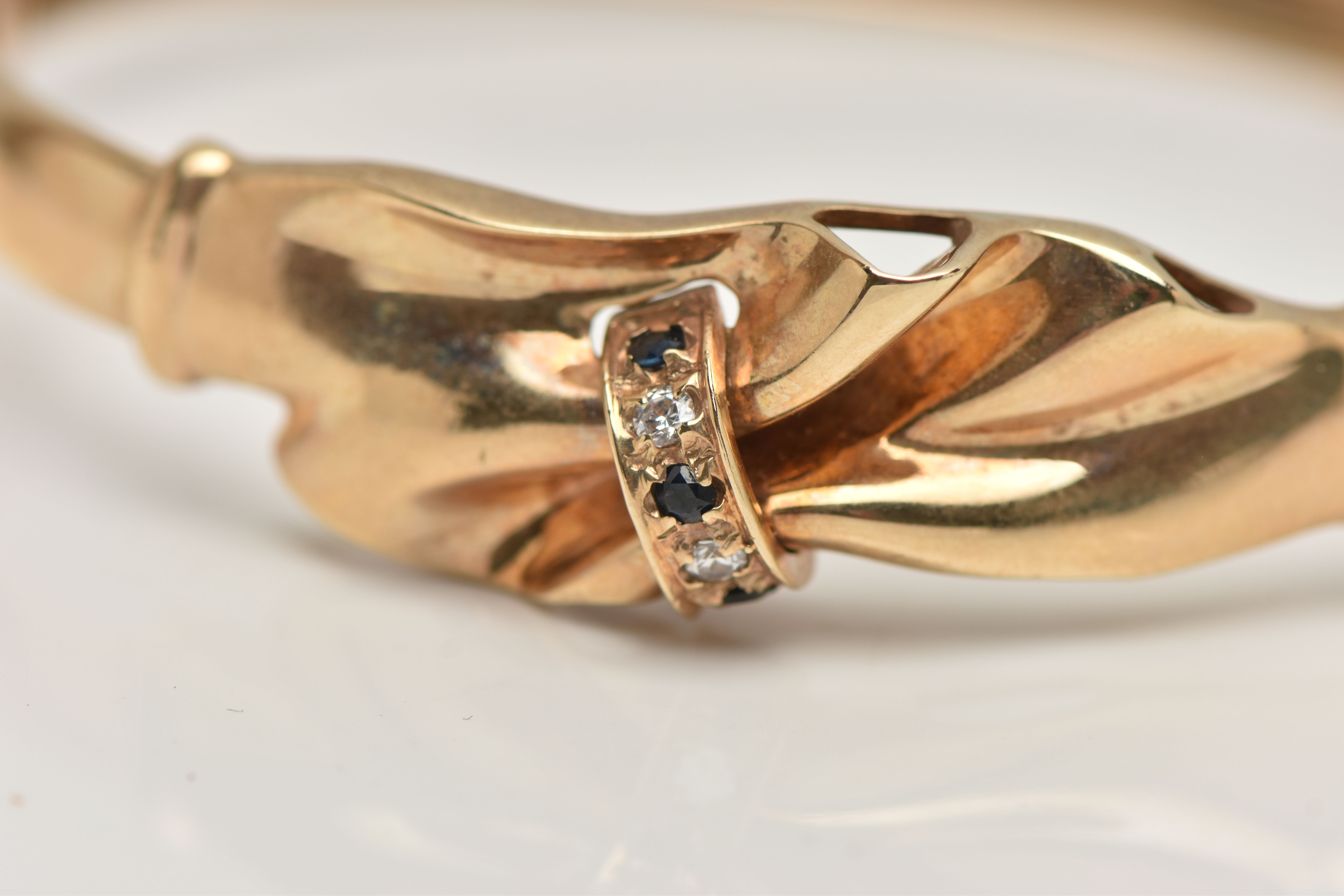 A 9CT GOLD HINGED BANGLE, gathered swag detail, set with three circular cut blue sapphires and two - Image 2 of 4