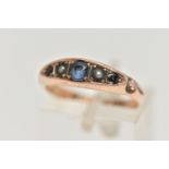 AN EDWARDIAN 9CT YELLOW GOLD GEM SET RING, Set with a principal sapphire, interspaced by two split