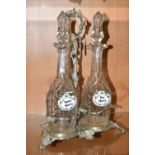 THREE LATE NINETEENTH CENTURY DECANTERS ON A PLATED STAND, the footed stand with foliate decoration,