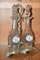 THREE LATE NINETEENTH CENTURY DECANTERS ON A PLATED STAND, the footed stand with foliate decoration,
