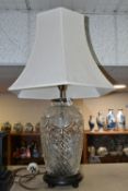 A CUT CRYSTAL TABLE LAMP, with bronzed effect base and cream shade, height to top of bulb fitting