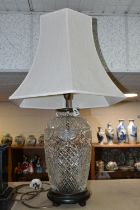 A CUT CRYSTAL TABLE LAMP, with bronzed effect base and cream shade, height to top of bulb fitting