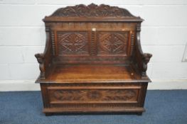 A 20TH CENTURY OAK MONKS BENCH, with foliate carved detail and lion armrests, with a hinged
