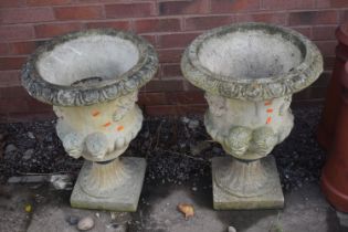 A PAIR OF WEATHERED COMPOSITE CAMPAGNA GARDEN URNS, with masks and foliate detail, on a square