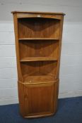 AN ERCOL ELM CORNER CUPBOARD, with two shelves, above a single cupboard door enclosing another